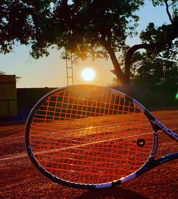 Raquete de tênis sobre a quadra de saibro ao pôr do sol